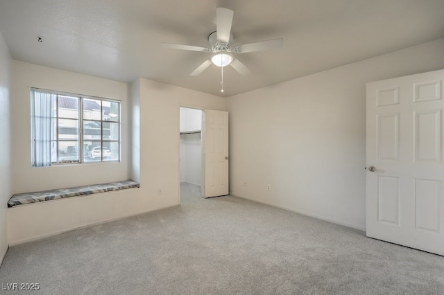 unfurnished bedroom featuring a ceiling fan, carpet, a walk in closet, and a closet