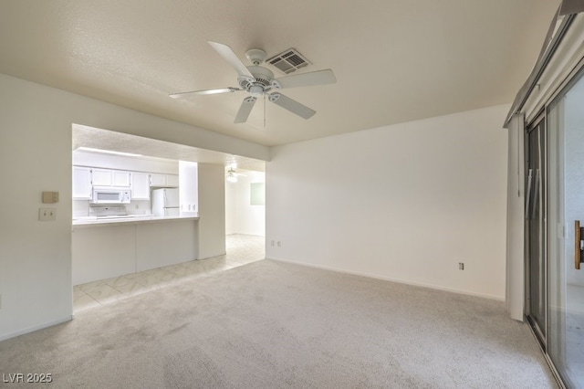 empty room with visible vents, a ceiling fan, and light colored carpet