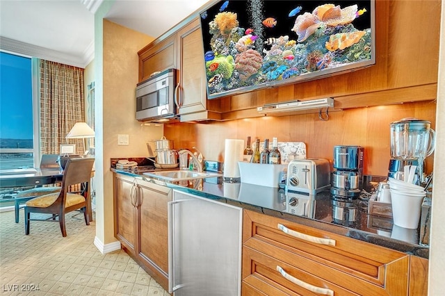 kitchen with dark stone countertops, ornamental molding, and sink