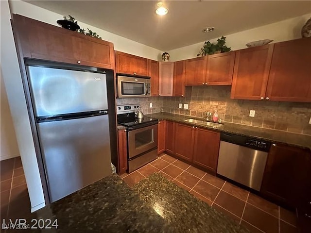 kitchen featuring dark stone counters, tile patterned floors, sink, appliances with stainless steel finishes, and tasteful backsplash