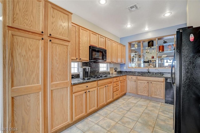 kitchen with sink, light brown cabinets, dark stone counters, light tile patterned floors, and black appliances