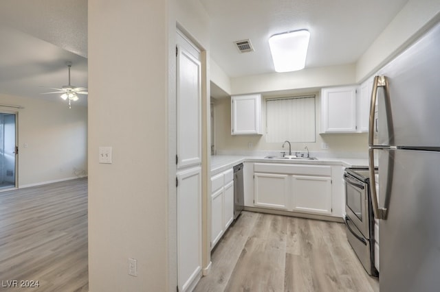 kitchen featuring appliances with stainless steel finishes, white cabinetry, sink, light hardwood / wood-style floors, and a textured ceiling