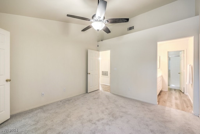 unfurnished bedroom featuring ceiling fan, lofted ceiling, connected bathroom, and light colored carpet