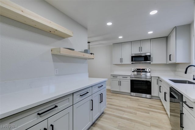 kitchen with white cabinets, appliances with stainless steel finishes, light hardwood / wood-style flooring, and sink