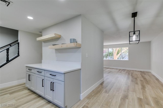 kitchen with white cabinets, decorative light fixtures, and light hardwood / wood-style floors