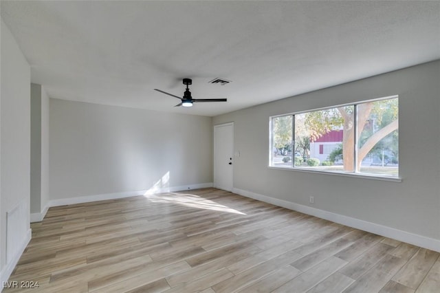 empty room with ceiling fan and light hardwood / wood-style flooring