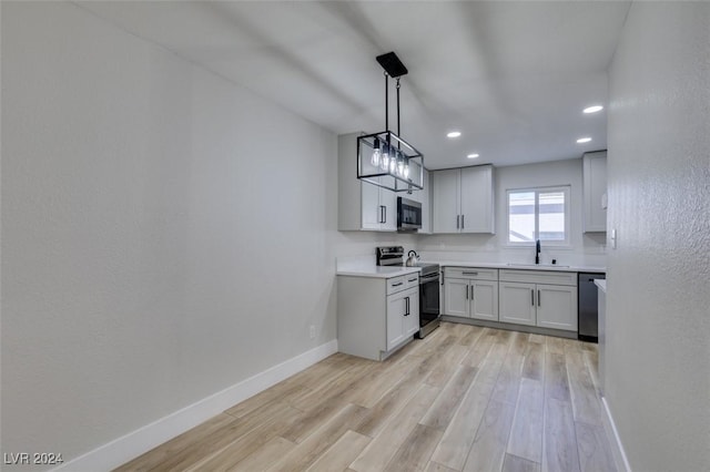 kitchen with white cabinetry, sink, hanging light fixtures, light hardwood / wood-style flooring, and appliances with stainless steel finishes