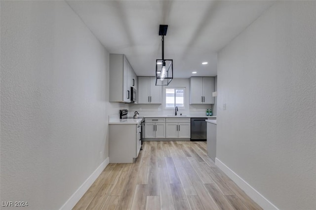 kitchen featuring light wood-type flooring, stainless steel appliances, sink, white cabinets, and hanging light fixtures