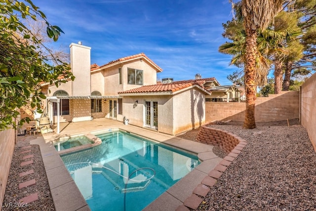 rear view of property featuring a pool with hot tub, a patio area, and french doors