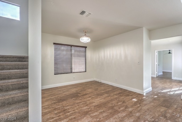 unfurnished room with ceiling fan with notable chandelier and dark hardwood / wood-style flooring