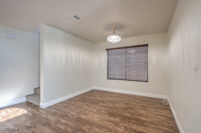 unfurnished room with dark hardwood / wood-style floors and a notable chandelier