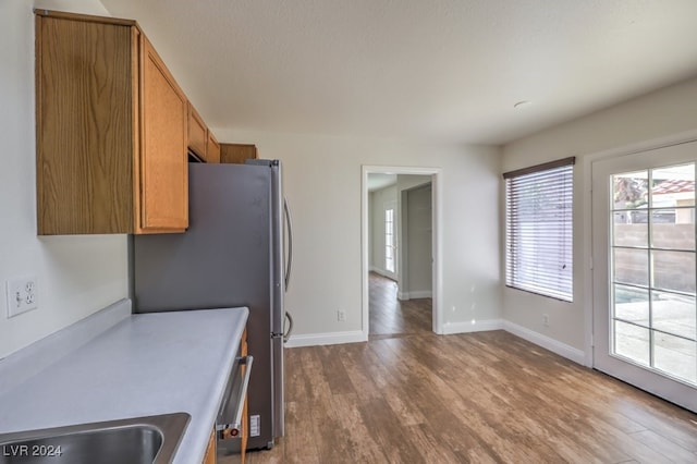 kitchen with stainless steel refrigerator, sink, and dark wood-type flooring