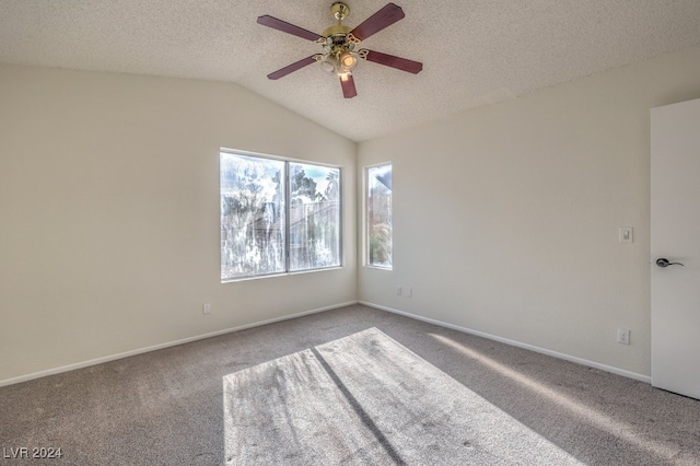 carpeted spare room featuring a textured ceiling, vaulted ceiling, and ceiling fan