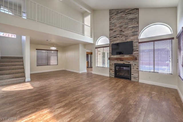 unfurnished living room featuring a fireplace, high vaulted ceiling, wood-type flooring, and beamed ceiling