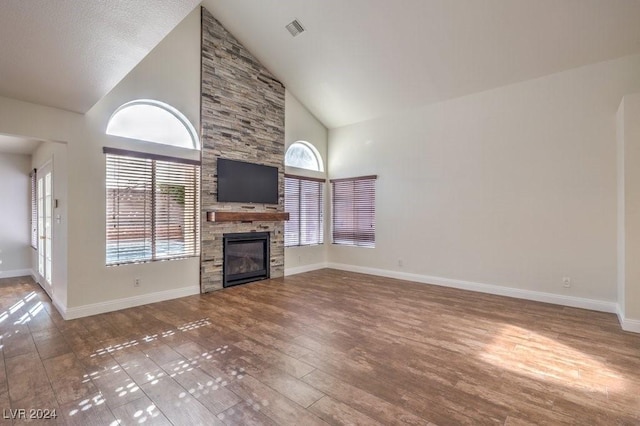 unfurnished living room with wood-type flooring, high vaulted ceiling, and a stone fireplace