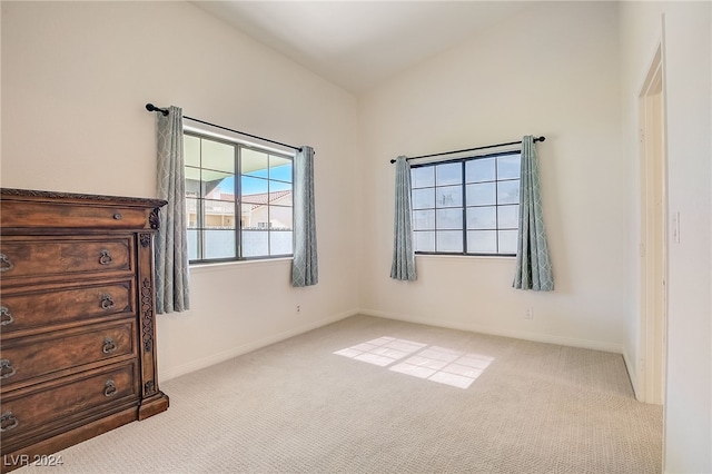 unfurnished bedroom with light colored carpet and vaulted ceiling