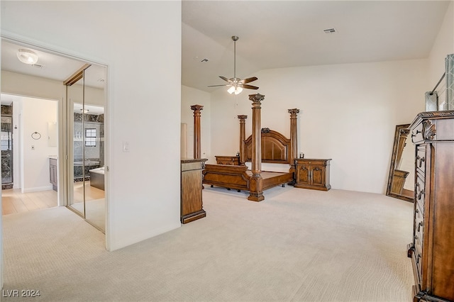 bedroom featuring light colored carpet, vaulted ceiling, ceiling fan, and ensuite bathroom