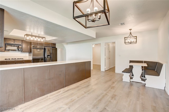 kitchen featuring kitchen peninsula, light hardwood / wood-style floors, a textured ceiling, and appliances with stainless steel finishes