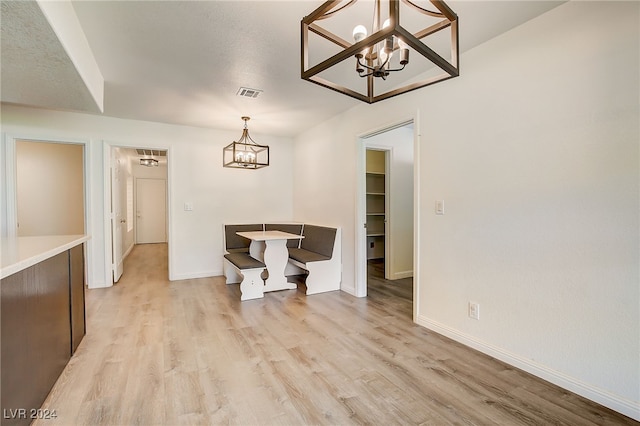 dining room with a chandelier, a textured ceiling, and light hardwood / wood-style flooring