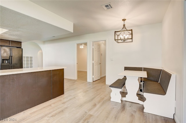 dining area featuring a textured ceiling, light wood-type flooring, and an inviting chandelier