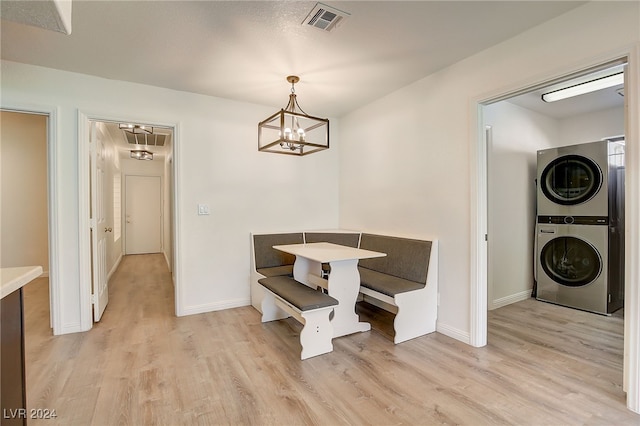 dining room featuring a notable chandelier, stacked washer / dryer, and light hardwood / wood-style flooring