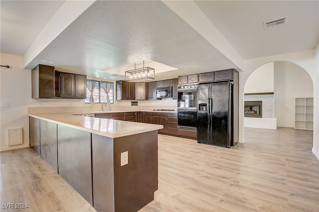 kitchen featuring black appliances, dark brown cabinetry, light wood-type flooring, a textured ceiling, and kitchen peninsula