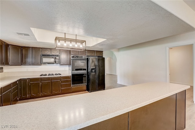 kitchen featuring pendant lighting, black appliances, a raised ceiling, a textured ceiling, and dark brown cabinetry