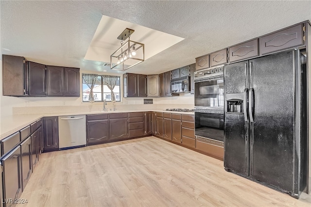 kitchen featuring black appliances, pendant lighting, a raised ceiling, and light hardwood / wood-style flooring