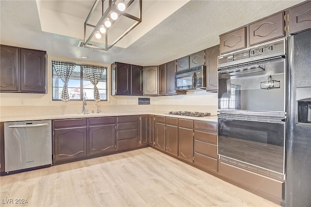 kitchen featuring sink, light hardwood / wood-style flooring, a textured ceiling, dark brown cabinets, and black appliances