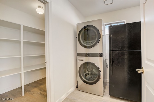 laundry room with light hardwood / wood-style floors and stacked washer and clothes dryer