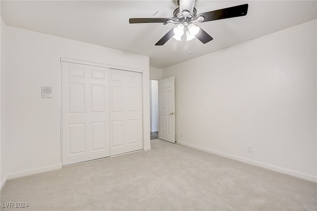 unfurnished bedroom featuring light carpet, a closet, and ceiling fan