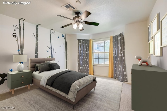 carpeted bedroom with ceiling fan and a textured ceiling