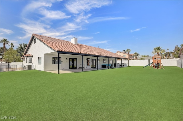 rear view of property featuring a playground, a yard, and a patio