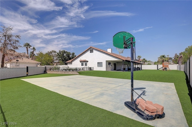 view of basketball court featuring a playground and a lawn