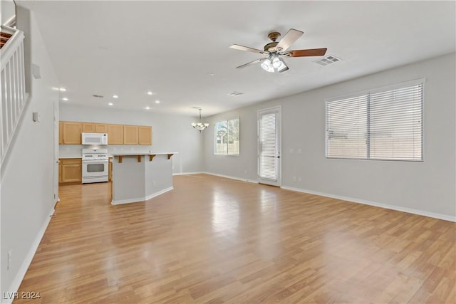 unfurnished living room featuring ceiling fan with notable chandelier and light hardwood / wood-style flooring