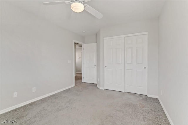 unfurnished bedroom featuring ceiling fan, a closet, and light colored carpet