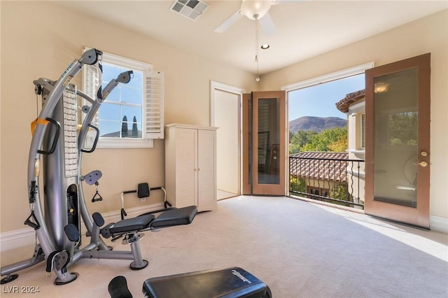 exercise room with a mountain view, carpet, french doors, and ceiling fan