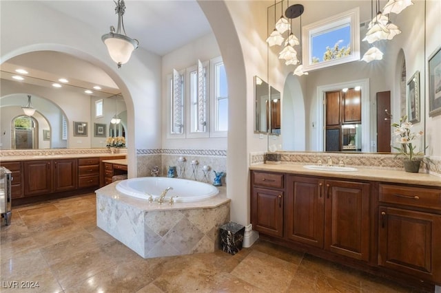 bathroom with a relaxing tiled tub and vanity