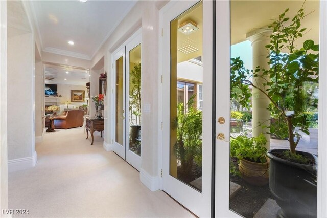 doorway to outside with ornamental molding, light carpet, and french doors