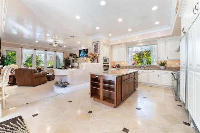 kitchen featuring stainless steel appliances, a kitchen island, white cabinetry, and a healthy amount of sunlight