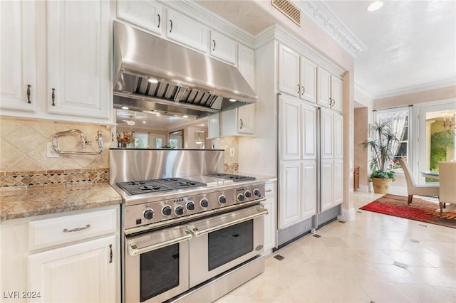 kitchen featuring light stone countertops, backsplash, white cabinetry, and double oven range