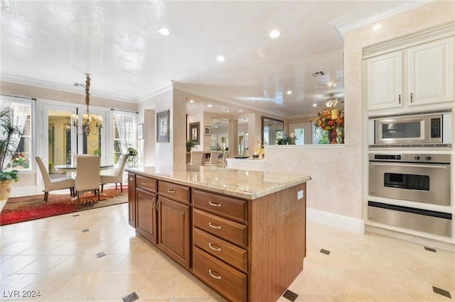 kitchen with a notable chandelier, appliances with stainless steel finishes, decorative light fixtures, a kitchen island, and ornamental molding