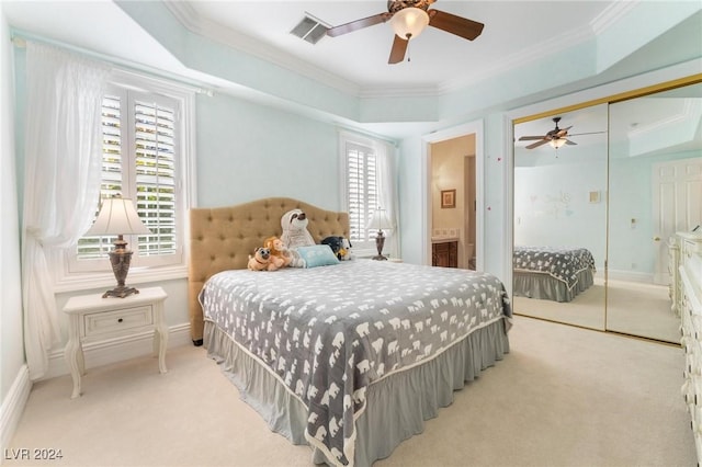 carpeted bedroom with a raised ceiling, multiple windows, ceiling fan, and a closet