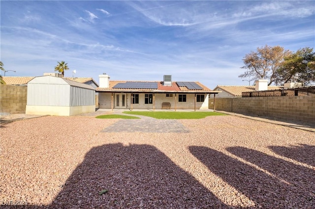 back of house featuring solar panels and a storage shed