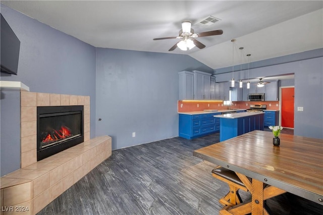 kitchen featuring blue cabinetry, a center island, hanging light fixtures, lofted ceiling, and a kitchen bar