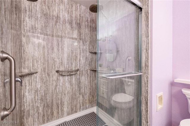 bathroom featuring toilet and a shower with shower door