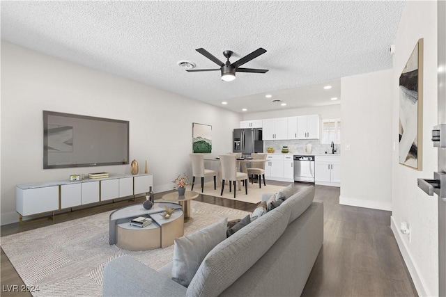 living room with wood-type flooring, a textured ceiling, ceiling fan, and sink