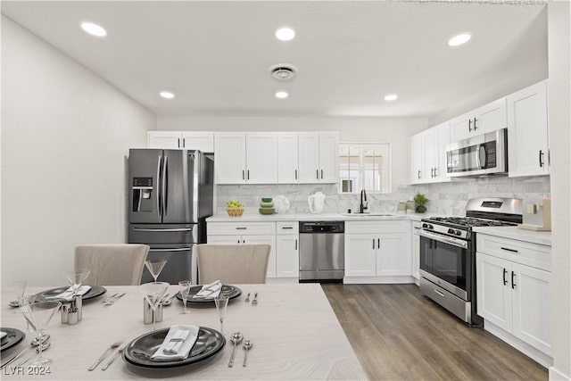 kitchen with sink, dark wood-type flooring, stainless steel appliances, decorative backsplash, and white cabinets