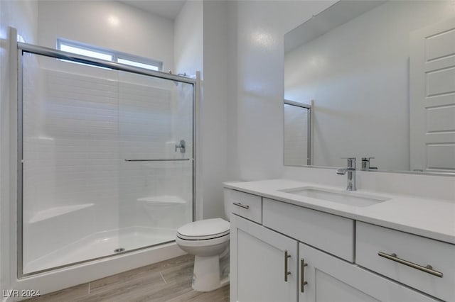 bathroom with hardwood / wood-style floors, vanity, toilet, and walk in shower