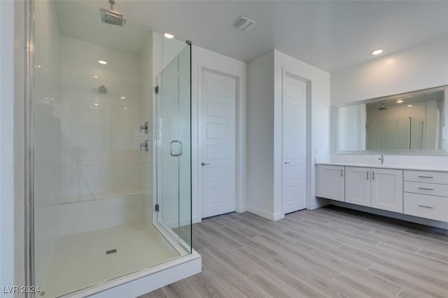 bathroom featuring hardwood / wood-style floors, vanity, and a shower with shower door